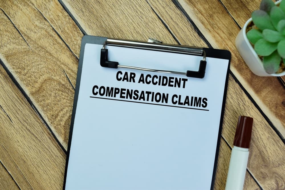 Car accident compensation claims concept written on paperwork, isolated on a wooden table.
