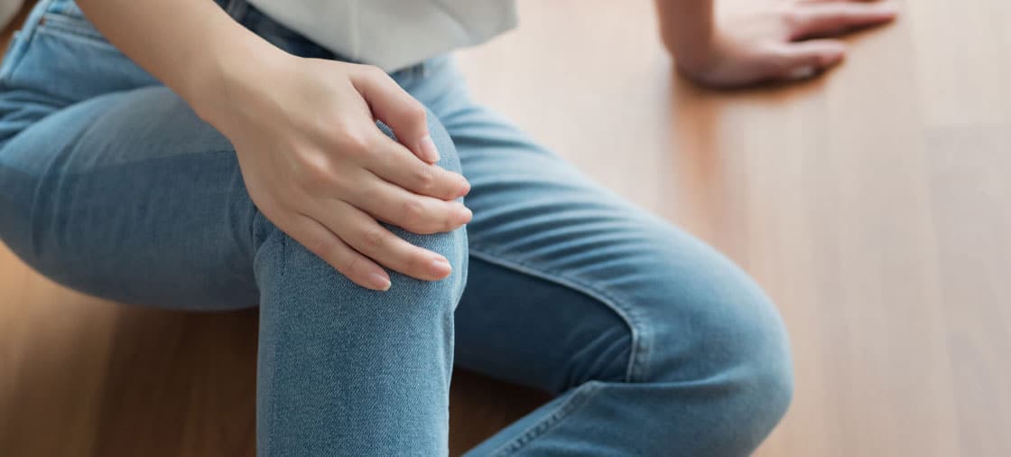 woman clutching her knee in pain