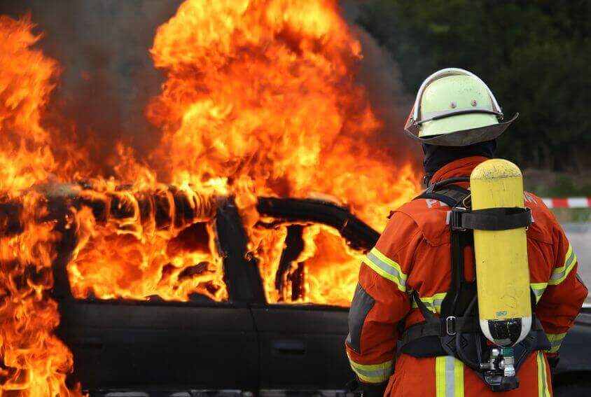 Fireman blowing out a fire on a car after a bad crash
