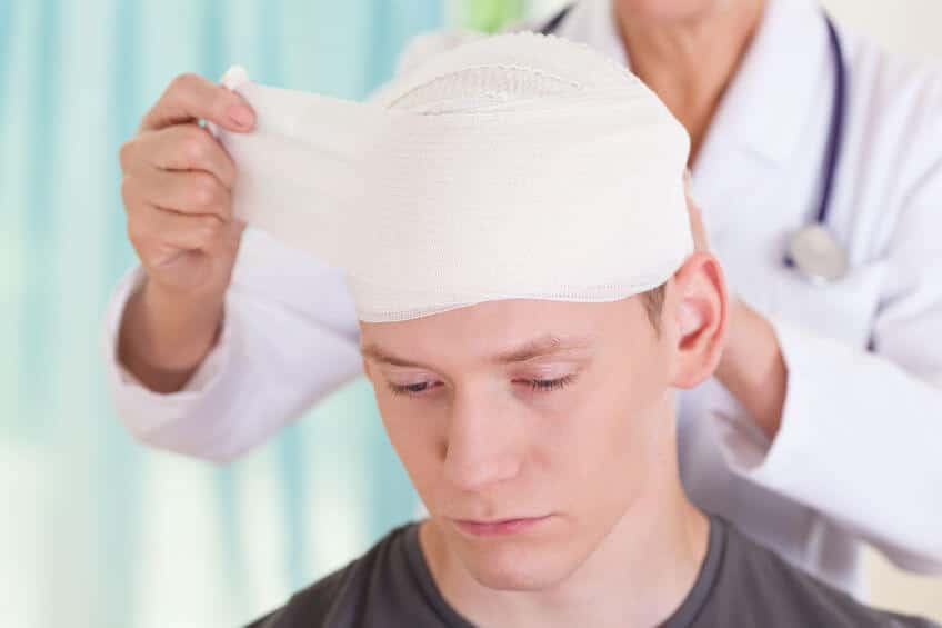 Man with a traumatic brain injury getting head wrapped by doctor.