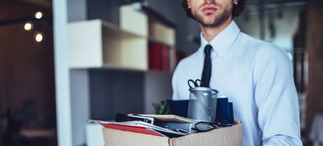 Man who was fired unfairly leaving his office with a box of his belongings