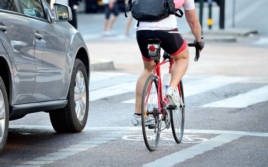 cyclist riding next to car.