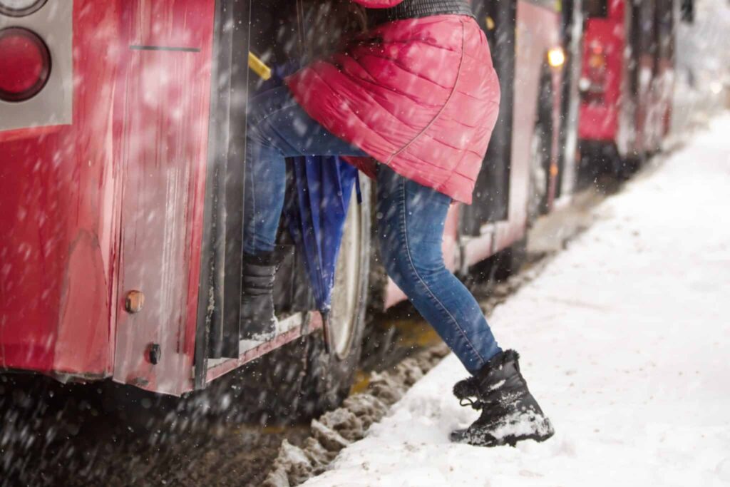 Person getting in the bus in the snow.