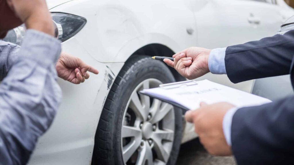 Insurance adjuster looking at damaged car in personal injury claim
