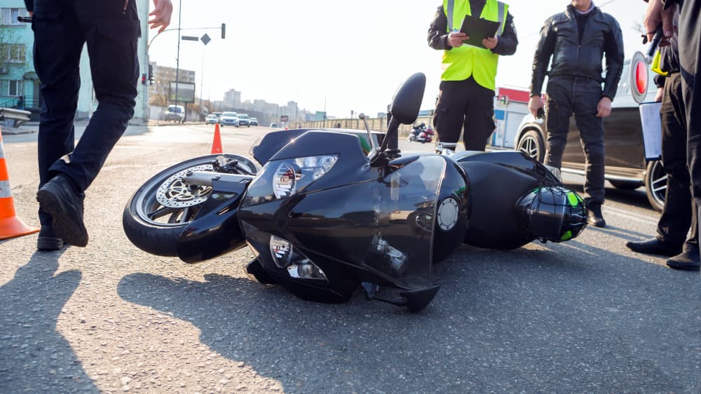 Policemen assessing the broken motorcycle after the accident on a road side.