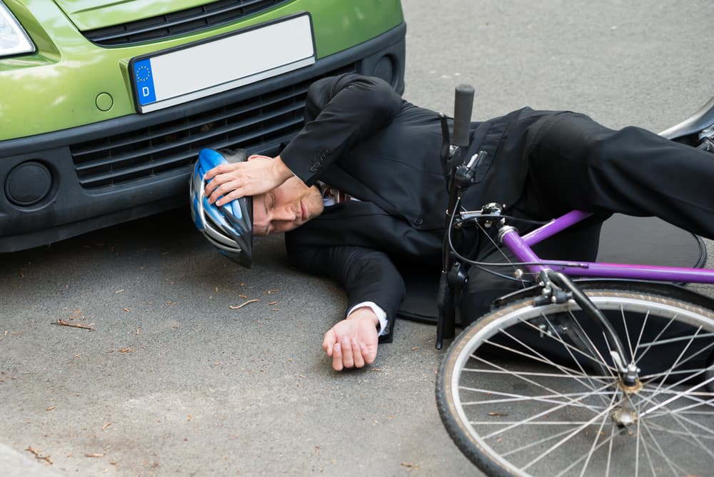 Injured male cyclist lying unconscious on the road after a cycling accident.