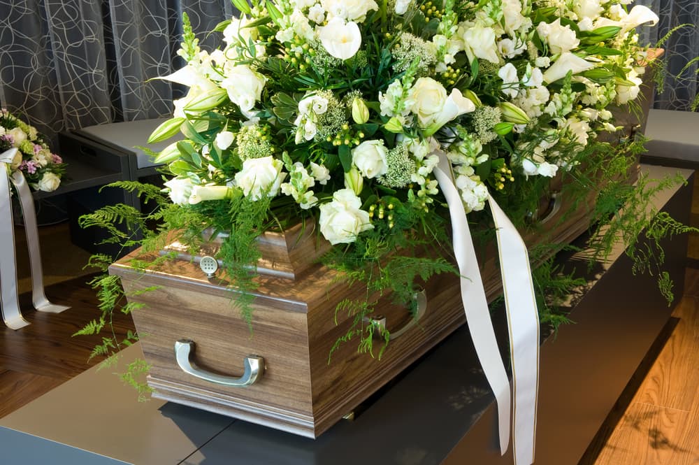 A flower-adorned coffin in a morgue, symbolizing loss and mourning.