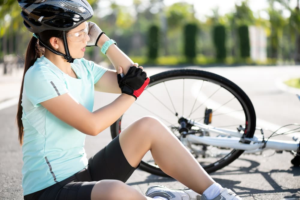 Young female cyclist sustains injuries after falling off her road bike. Bicycle accident results in an injured knee.