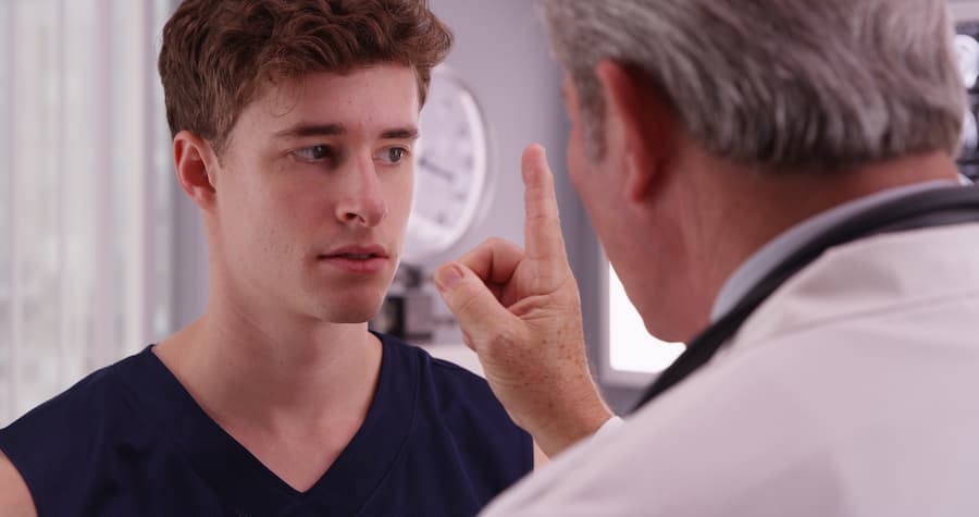 Young male being examined for a concussion from traumatic brain injury doctor.