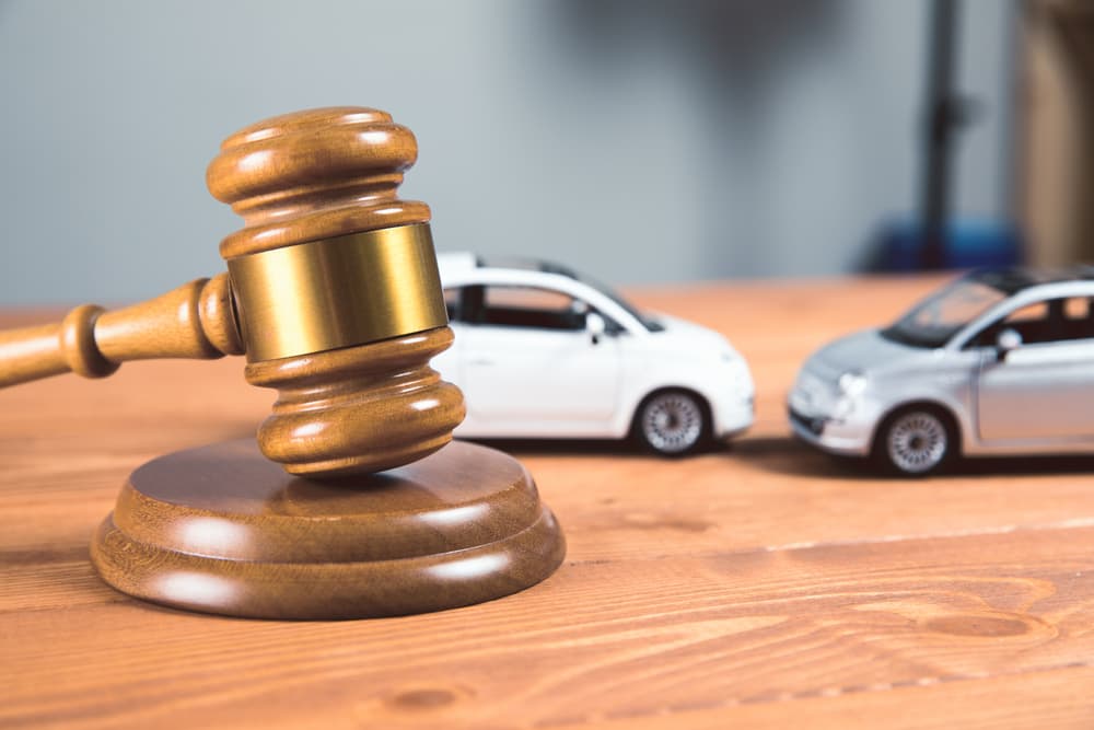 Image of a court gavel with toy cars on the table, representing a legal case related to a car accident.