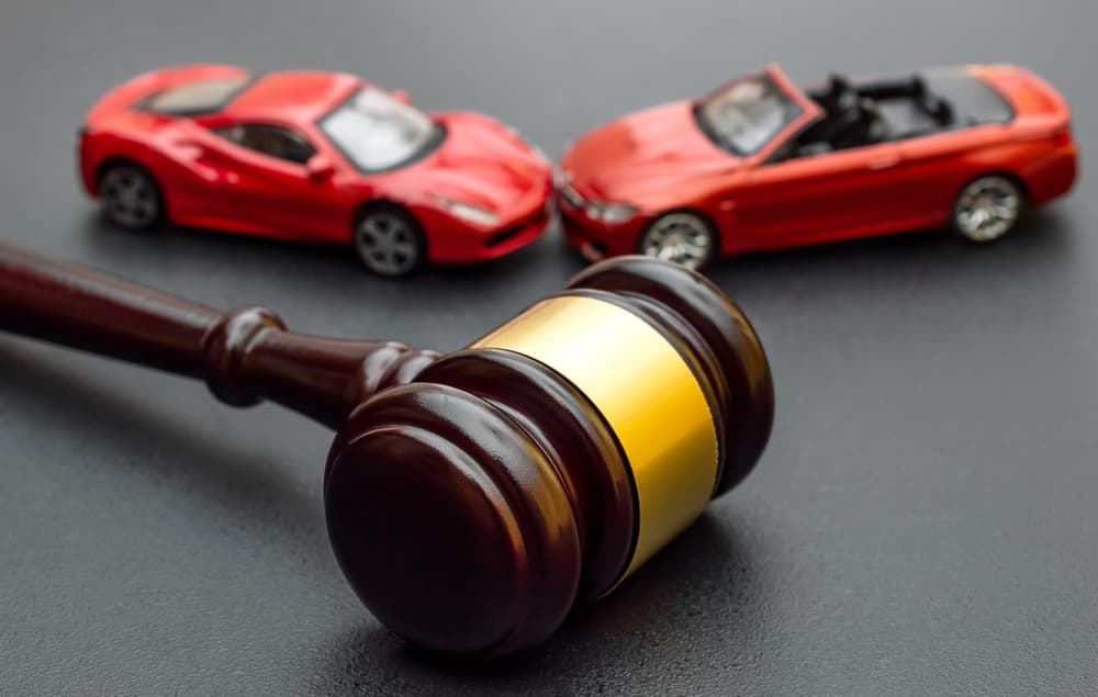 Toy cars beside judge gavel, representing legal judgment or decision regarding automobile-related matter.