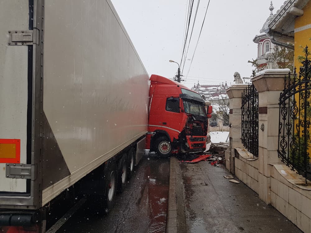 A large red truck involved in an accident causing the demolition of a marble fence.