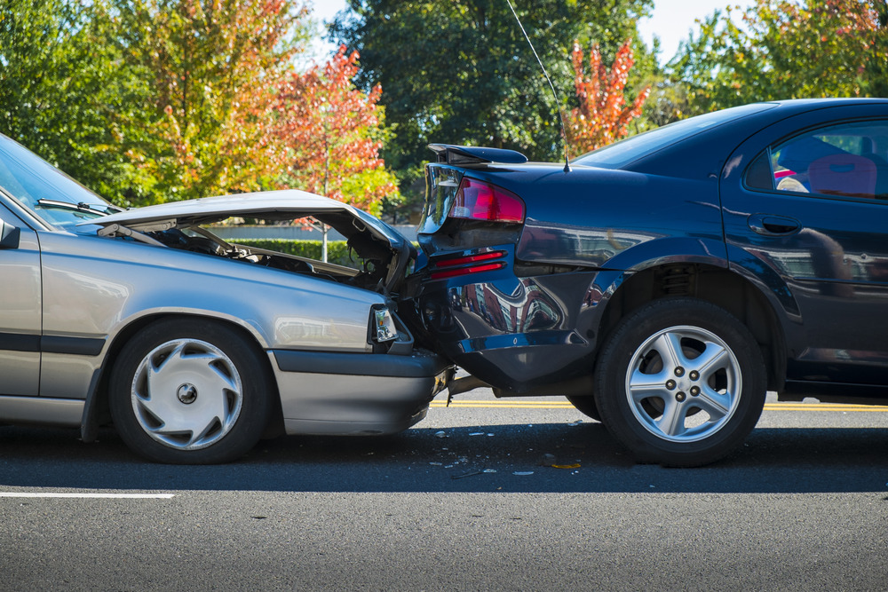 Two cars damaged after silver car hitting blue car from the back.